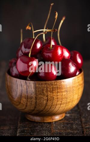 Ciotola piena di ciliegie rosse scure con steli isolati su uno sfondo bianco Foto Stock