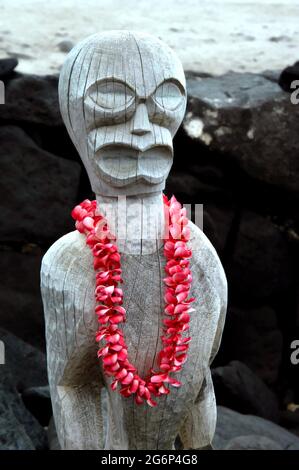 La fresca plumeria lei pende dal collo di un antico tiki a Puuhonua o Honaunau National Historical Park sulla Big Island delle Hawaii. Foto Stock