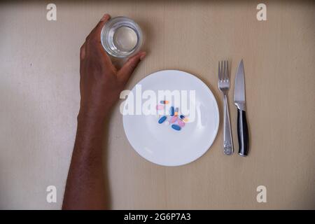 Foto in alto di un piatto con pillole e forcelle e un bicchiere d'acqua. Concetto di abuso di droghe e medicinali Foto Stock