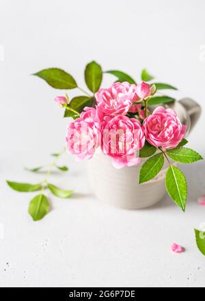 Bel bouquet di mini rose rosa in una piccola tazza di caffè espresso. Foto Stock