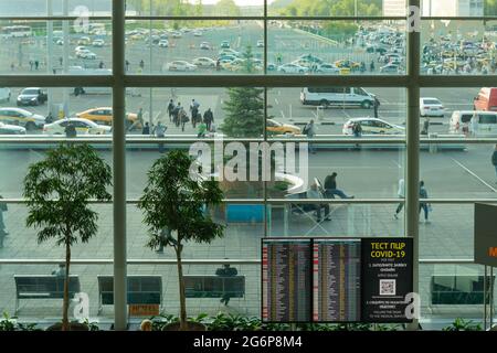 Al di fuori dell'aeroporto internazionale Domodedovo visto attraverso la finestra dall'interno, sopra le partenze mostra nel terminal, DME, Mosca, Russia Foto Stock