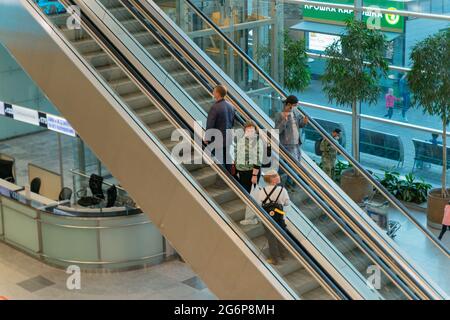 Passeggeri sulla scala mobile nella sala principale terminal dell'aeroporto internazionale Domodedovo, DME, Mosca, Russia Foto Stock