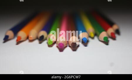 Primo piano le matite di colore arcobaleno sono puntate alla fotocamera con sfondo bianco Foto Stock