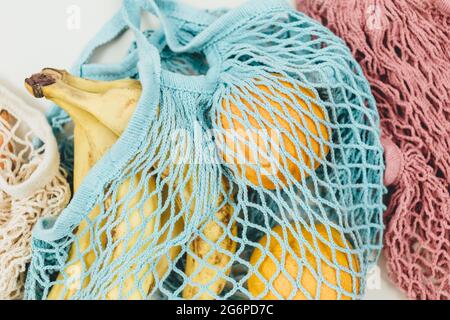 Verdure fresche in un sacchetto di maglia di cotone riutilizzabile beige blu su sfondo beige. Borsa per la spesa ecologica. Zero rifiuti alimentari concetto. Stile di vita sostenibile Foto Stock