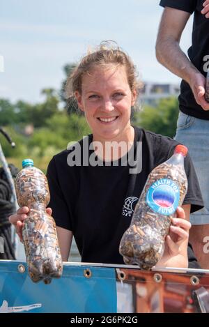 28 giugno 2021, Sassonia-Anhalt, Magdeburgo: Mona Rittinghaus (31) del peschereccio di ricerca 'Aldebaran' mostra bottiglie di PET riempite di mozziconi di sigaretta. Insieme agli scienziati, sta trascorrendo quattro settimane sull'Elba per attirare l'attenzione sul problema della plastica globale. Sta raccogliendo mozziconi di sigaretta con il sostegno di numerose iniziative ambientali lungo l'Elba. Questa è la più grande campagna di raccolta del suo genere in Germania. Si intende richiamare l'attenzione sul fatto che i mozziconi di sigaretta scartati in modo incauto possono contaminare l'acqua fluviale. Foto: Stephan Schulz/dpa-Zentralbild/ZB Foto Stock