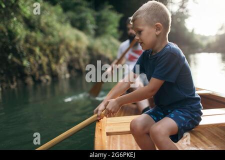 Ragazzo giovane impara a remare in canoa Foto Stock