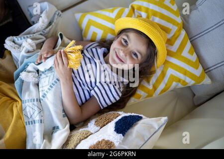 Felice carina bambina in estate giallo panama sdraiato sul divano rilassante sulla terrazza all'aperto Foto Stock