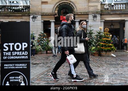 File foto datata 18/12/20 di persone che camminano oltre un segno che consiglia la distanza sociale a Covent Garden a Londra. Più di 100 scienziati e medici hanno firmato una lettera che accusa il governo britannico di condurre un 'esperimento disangoso e non etico' e lo invita a riconsiderare i suoi piani di abbandonare tutte le restrizioni del coronavirus. Data di emissione: Giovedì 8 luglio 2021. Foto Stock