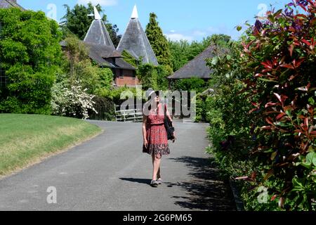 Giardini di Stocktonbury. Visitatore in abito estivo e cappello da sole, ammira le piante, i fiori e gli edifici antichi Foto Stock