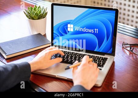 Grecia Atene, 8 luglio 2021. Uomo che lavora con un laptop, Windows 11 nuovo sistema operativo Microsoft sullo schermo del computer, business Office sfondo. Foto Stock