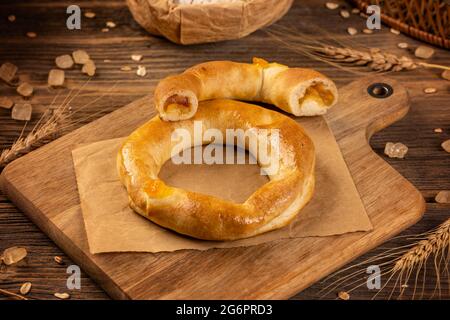 Bagel freschi e dolci fatti in casa ripieni di marmellata di mele su sfondo di legno Foto Stock