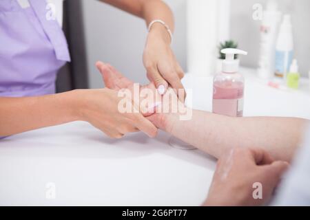 Un'immagine tagliata di un uomo irriconoscibile che ha le mani massaggiate dal manicurista Foto Stock