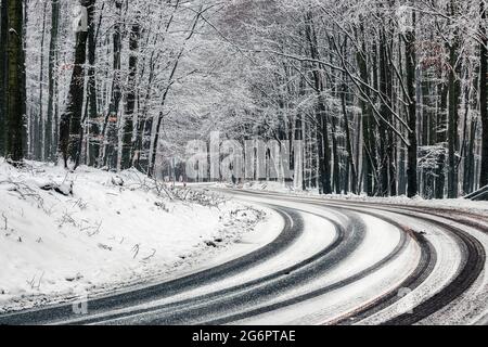 Kekesteto, Ungheria - strada invernale tortuosa sulle montagne di Matra vicino Kekesteto. Strada asfaltata curva con alberi innevati nella foresta in un inverno freddo Foto Stock