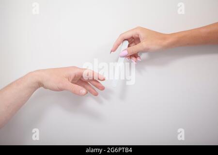 Mano maschio che raggiunge la mano del manicurista con filer unghie Foto Stock