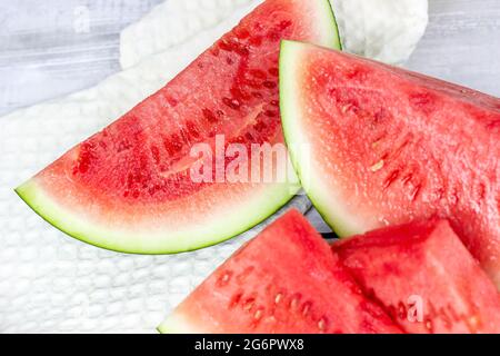 Fette di anguria rosso dolce e verde in estate su sfondo chiaro del tavolo. Foto Stock