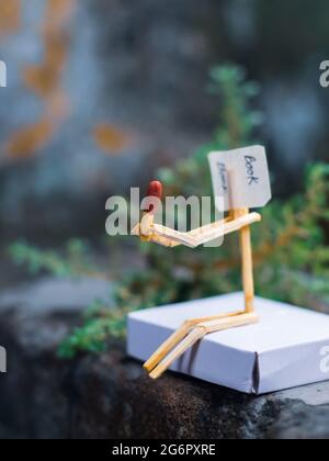 Concetto e idee di matchstick. Concetto e idee di lettura del libro. Matchstick lettura di un libro con sfondo verde. Foto Stock