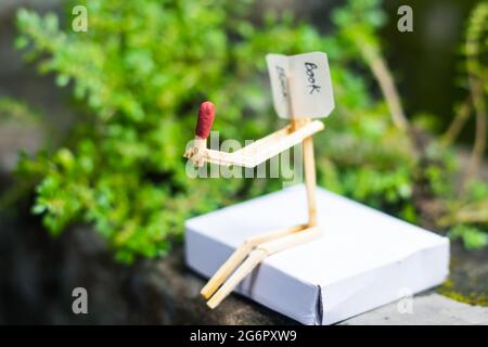 Concetto e idee di matchstick. Concetto e idee di lettura del libro. Matchstick lettura di un libro con sfondo verde. Foto Stock