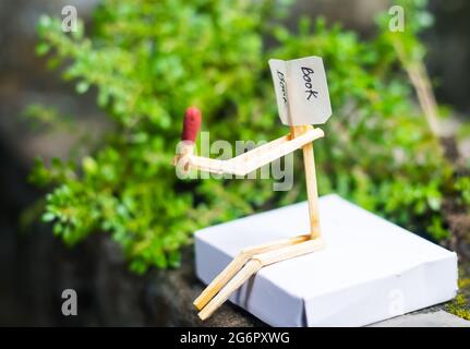 Concetto e idee di matchstick. Concetto e idee di lettura del libro. Matchstick lettura di un libro con sfondo verde. Foto Stock