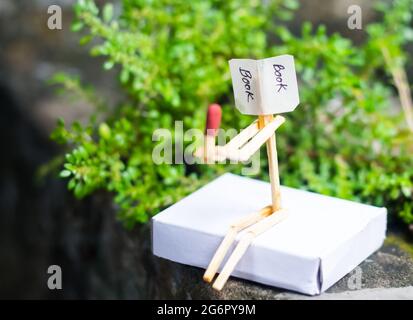 Concetto e idee di matchstick. Concetto e idee di lettura del libro. Matchstick lettura di un libro con sfondo verde. Foto Stock