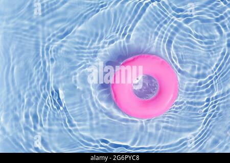 Anello di galleggiamento della piscina rosa che galleggia in una rinfrescante piscina blu. Vista dall'alto Foto Stock