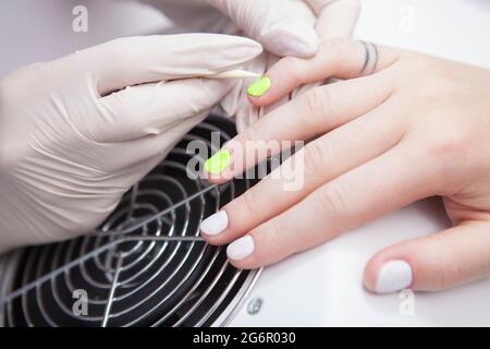 Primo piano di manicurista che applica smalto al neon Foto Stock
