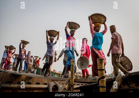 Una catena umana di facchini trasporta carbone, sabbia e ghiaia dalle chiatte ormeggiate presso la stazione di atterraggio di Aminbazar sul fiume Buriganga fuori Dhaka. Il Bangladesh si sta laureando dalla categoria LDC (paesi meno sviluppati), grazie in gran parte al lavoro estremamente duro della forza lavoro manuale a basso costo. Un facchino fa fra 80 e 140 USD al mese, secondo i Web site paylab.com e averagesalarysurvey.com Foto Stock