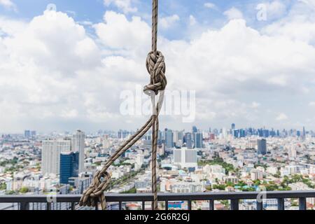 Corda bianca legata sulla barra di ferro sul tetto dell'edificio. Foto Stock