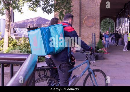 Il corriere Deliveroo sulla sua moto che consegna il cibo caldo al cliente, Londra, South Bank, Inghilterra, Regno Unito Foto Stock