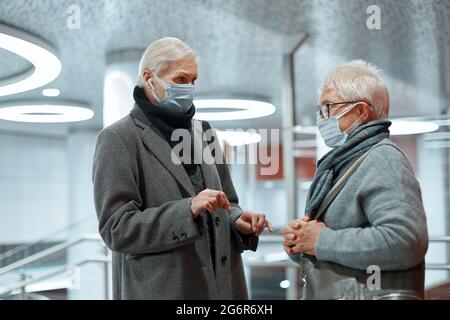 primo piano. due donne in maschere protettive parlano in piedi nell'edificio della stazione. Foto Stock