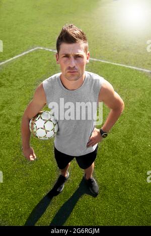 Giocatore di calcio con una palla in piedi nel campo Foto Stock