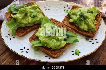Sandwich con spinaci, avocado, piselli verdi e uova su sfondo di legno Foto Stock