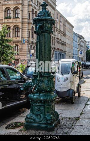 Nuovo e vecchio. Pompa d'acqua a mano storica e moderno scooter elettrico ENUU a Kreuzberg-Berlino Foto Stock