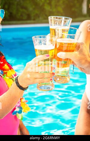 brindisi con tre bicchieri di birra in una piscina Foto Stock