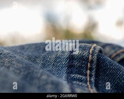 Macro fotografia delle pieghe di un paio di jeans che assomiglia a colline contro il cielo nuvoloso. Foto Stock