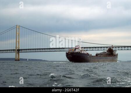 Grande freighter che passa attraverso lo stretto di Mackinac, passa tra i grandi Laghi Michigan e il lago Huron, Michigan, Big Mac Bridge sullo sfondo Foto Stock