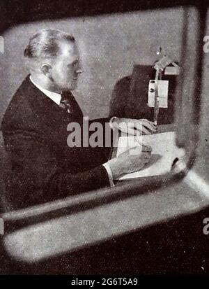 Una fotografia stampata molto presto di un annunciatore della BBC che legge la notizia . La BBC ha iniziato i servizi radiofonici quotidiani a Londra negli anni venti sulla stazione radio 2LO. Sotto la direzione generale di John Charles Walsham Reith, 33 anni, la BBC ha iniziato ad espandere i propri programmi il 14 dicembre 1922. Il primo ingegnere capo fu Peter Eckersley. Il 1927 ha visto la costituzione della British Broadcasting Corporation da parte di Royal Charter con Reith come suo primo Direttore Generale. John Logie Baird ha iniziato a sperimentare le trasmissioni televisive sulle frequenze della BBC nel novembre 1929. Foto Stock