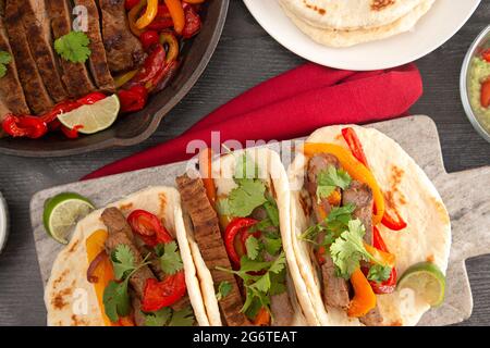 Fajitas di manzo con peperoni su un tavolo di legno scuro Foto Stock