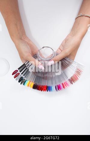 Vista dall'alto verticale ripresa ritagliata delle mani femminili che mantengono la tavolozza dei colori smalto per unghie Foto Stock