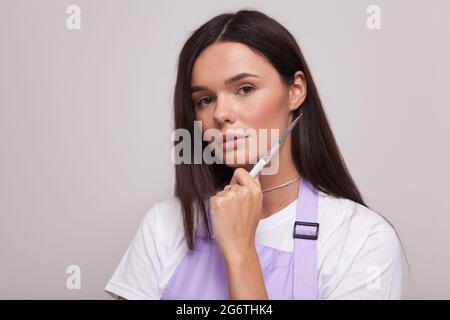 Primo piano ritratto di una bella donna che tiene pennello unghie Foto Stock