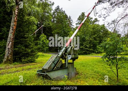 Una barriera per passaggio a livello rossa e bianca azionata a mano si trova nel giardino dell'ex stazione ferroviaria di Görsdorf a Lautertal, circondario di Coburgo, Baviera, Germania; una seconda è visibile sullo sfondo. La stazione si trovava sulla ferrovia Werra (Eisenach–Coburgo), aperta nel 1858; la sezione tra Eisfeld e Görsdorf non è stata più utilizzata dall'8 aprile 1945 ed è stata ufficialmente chiusa nel 1949. Foto Stock