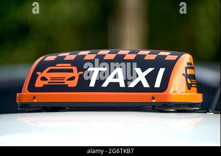 un cartello arancione del taxi si trova sul tetto dell'auto Foto Stock