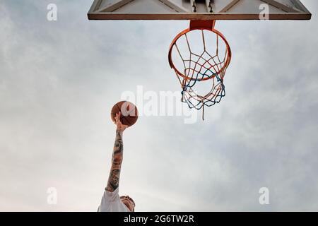 La mano getta il basket al cerchio Foto Stock