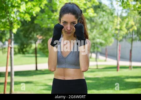 Nessuna persona binaria in mano si avvolge pronta a combattere guardando la telecamera. Muay thai, sport all'aperto. Foto Stock