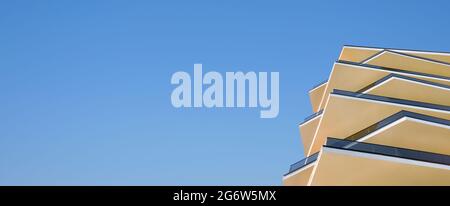 Edificio di architettura moderna, con una facciata in vetro e cemento, un mercato di proprietà con bandiera blu chiaro. Nuova facciata dell'edificio degli appartamenti Foto Stock