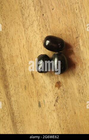 Frutti di prugne di Giava o frutti di syzygium su superficie di legno isolata, vista dall'alto, frutti di bacche blu, nuova immagine Foto Stock