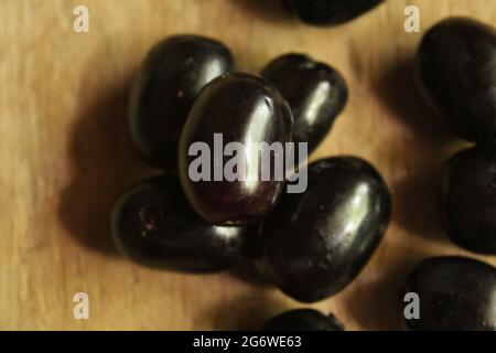 Frutti di prugne di Giava o frutti di syzygium su superficie di legno isolata, vista dall'alto, frutti di bacche blu, nuova immagine Foto Stock