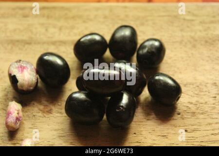 Frutti di prugne di Giava o frutti di syzygium su superficie di legno isolata, vista dall'alto, frutti di bacche blu, nuova immagine Foto Stock