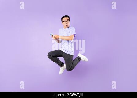 Ritratto di un uomo asiatico saltante, isolato su sfondo viola Foto Stock