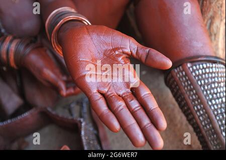 NAMIBIA. HIMBA DONNA METTENDO IL TRADIZIONALE ROSSO OIGNMENT (OTJIRE) PER PROTEGGERE LA SUA PELLE DAL SOLE, L'ARIA SECCA E GLI INSETTI. QUESTO OIGNMENT È MA Foto Stock
