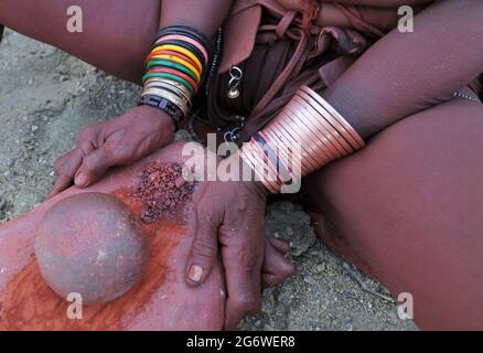 NAMIBIA. HIMBA DONNA CHE PREPARA IL ROSSO TRADIZIONALE OIGNMENT (OTJIRE) CHE USA PER PROTEGGERE LA SUA PELLE DAL SOLE, L'ARIA SECCA E GLI INSETTI. QUESTO OIG Foto Stock